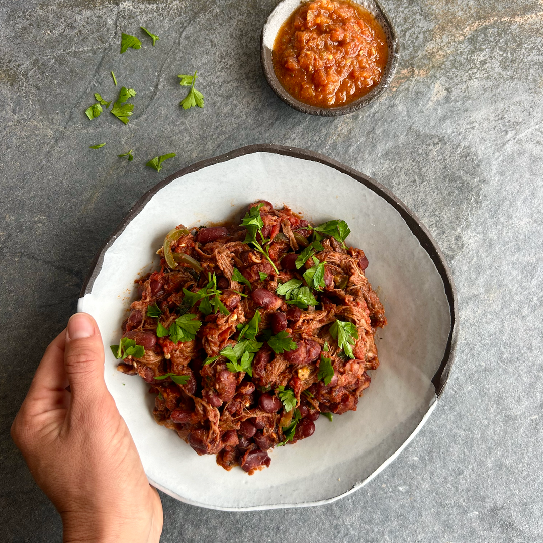 Hearty shredded beef and bean chilli with fresh herbs, served in a rustic bowl