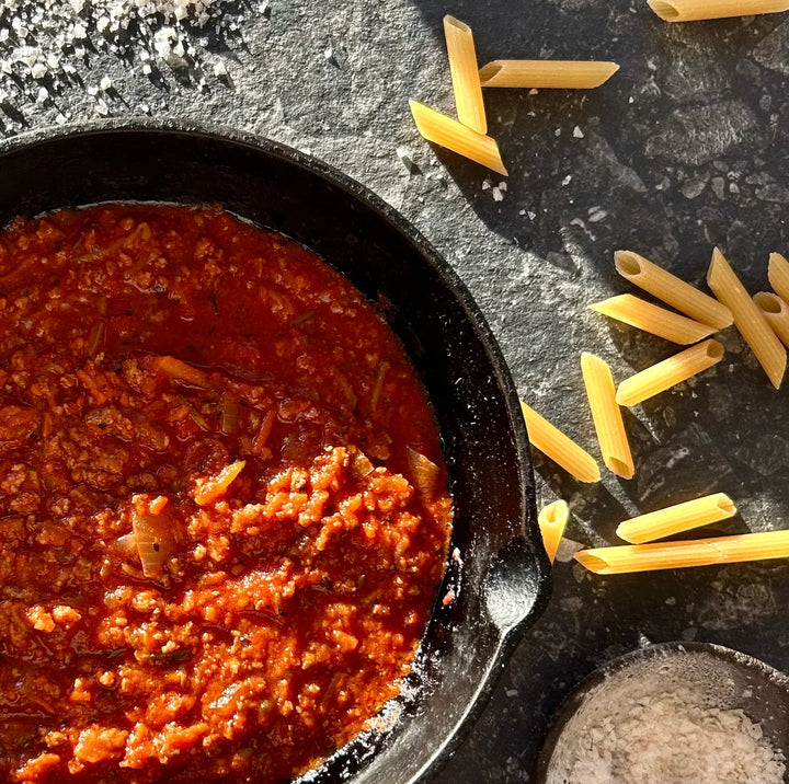Hearty tomato and beef bolognese sauce with penne pasta and coarse salt