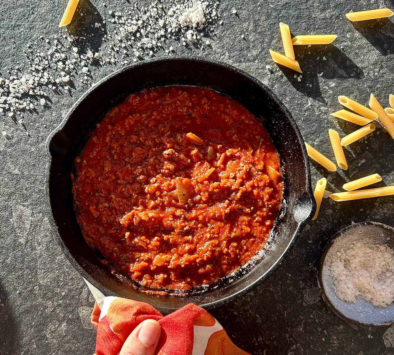 Hearty tomato and beef bolognese sauce with penne pasta and coarse salt