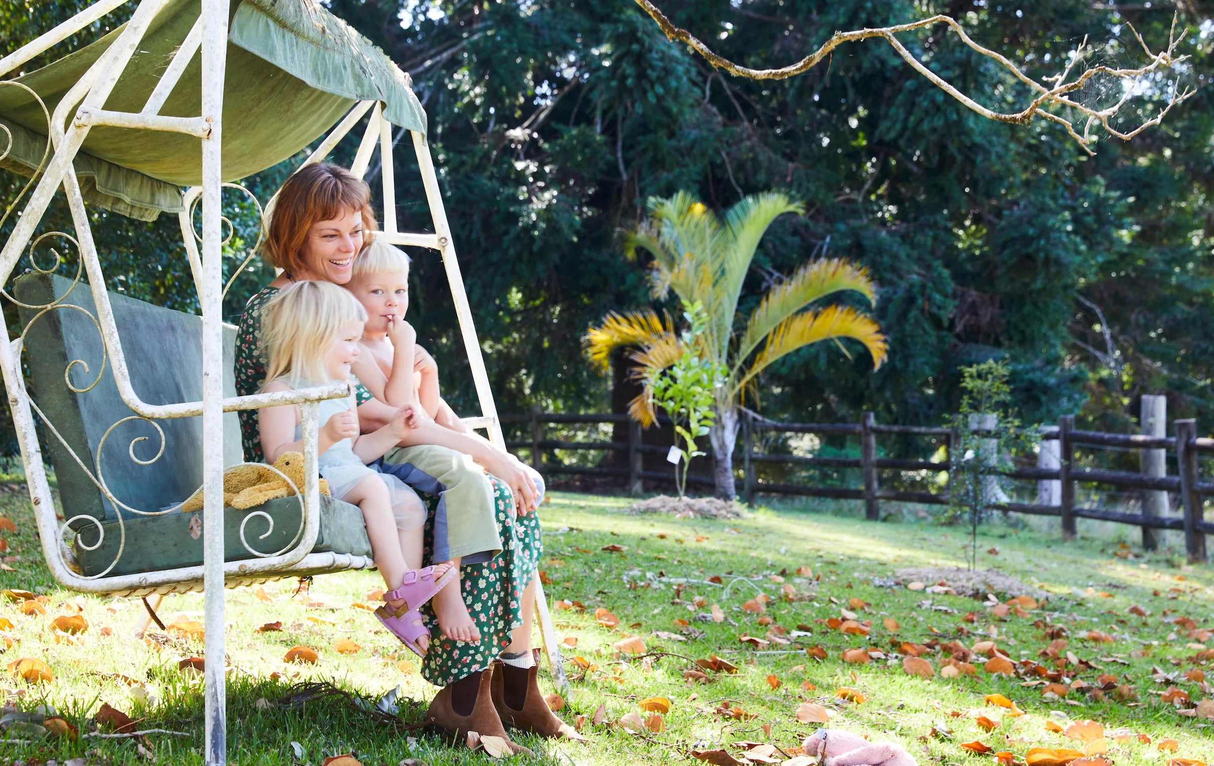Woman with two children sitting on a swing in a garden